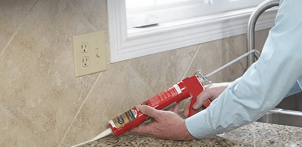 Handyman applying caulk along a kitchen backsplash and countertop seam in Las Vegas, NV