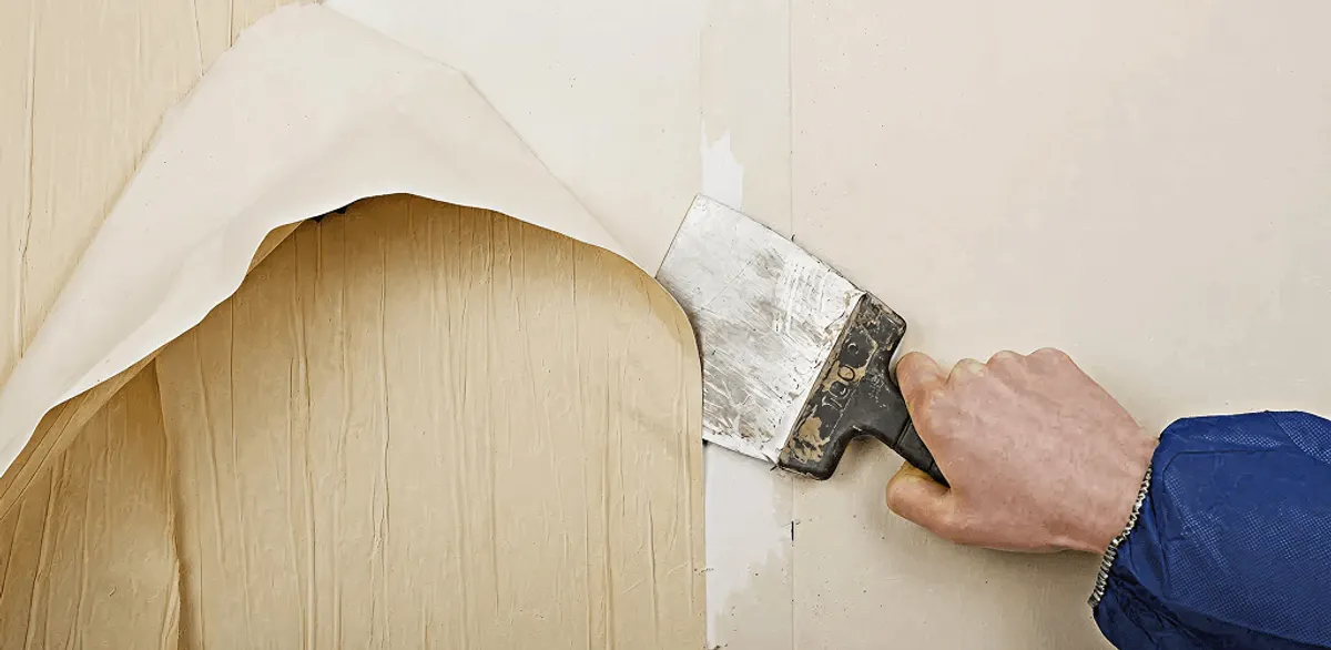 Handyman removing wallpaper with a scraper for wall preparation in Las Vegas, NV