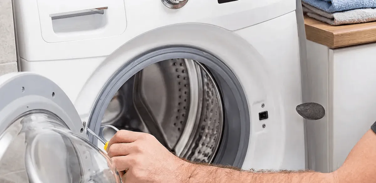 Handyman repairing a front-load washing machine and inspecting the drum in Las Vegas, NV
