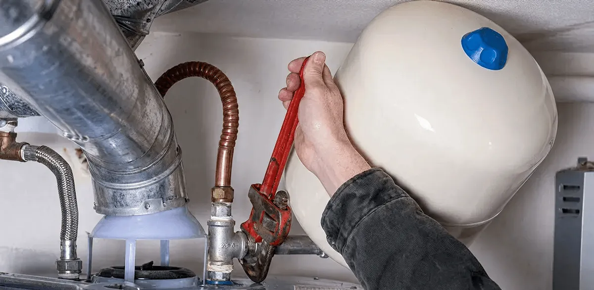 Water heater repair technician tightening plumbing connections near a tank unit in Las Vegas, NV